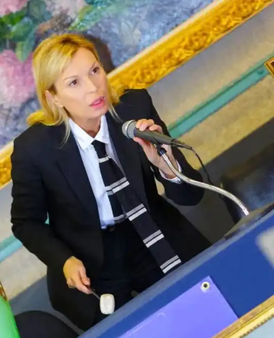 A performer in a black suit and white tie holding a microphone.