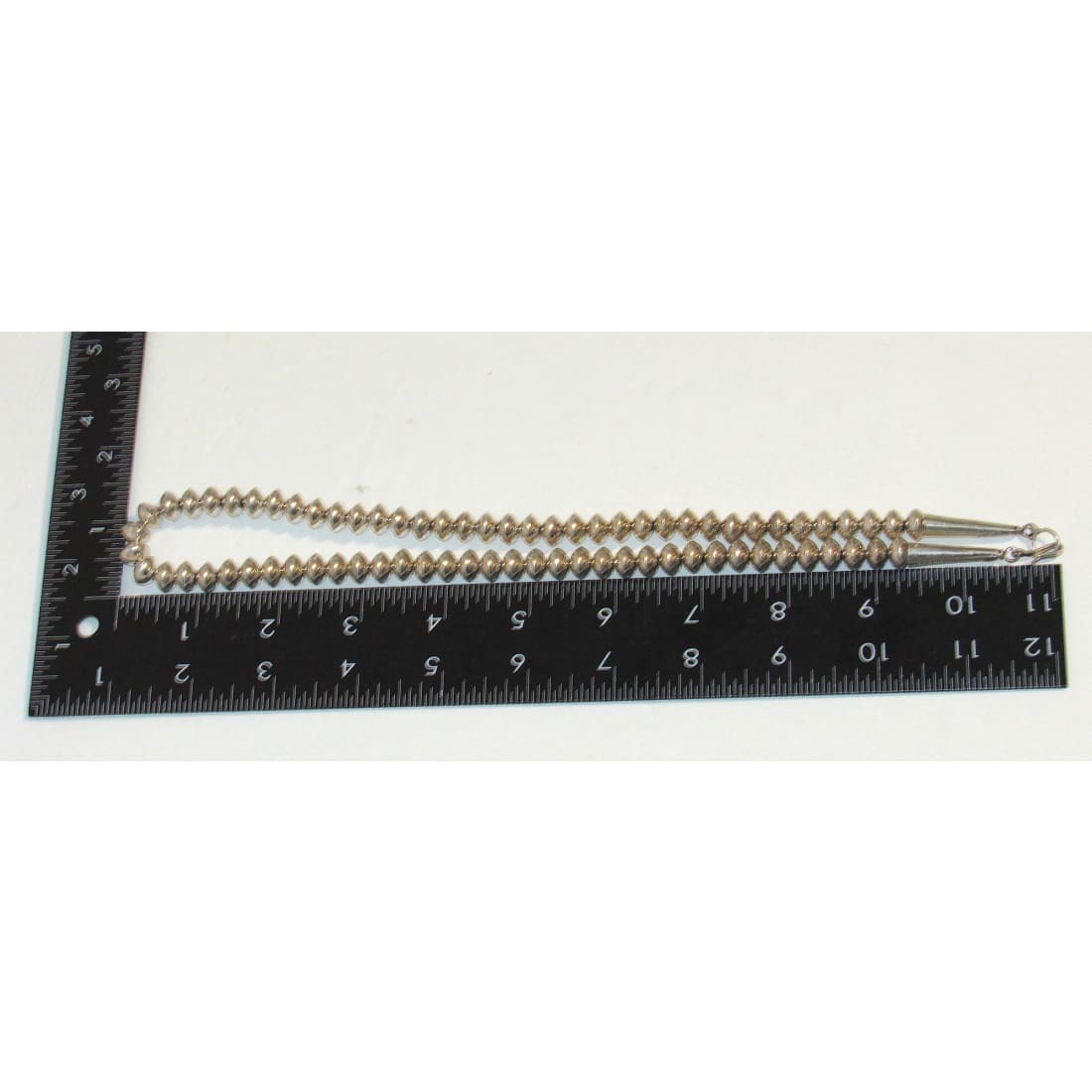 Vintage Navajo pearls necklace with silver clasp laid next to ruler for size measurement