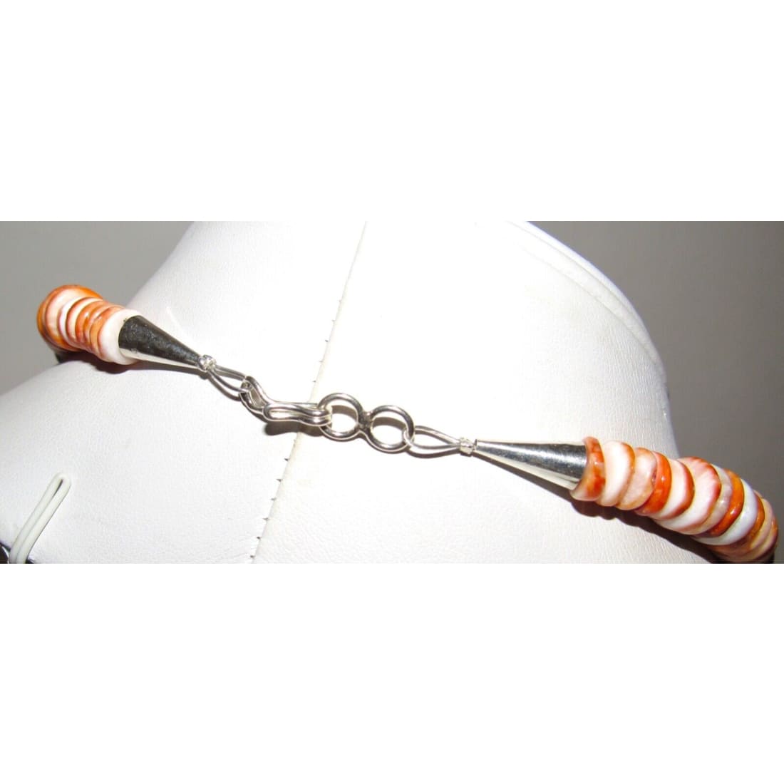 Navajo Tommy Singer orange spiny oyster necklace showcasing vibrant shells and sterling silver clasp on display.
