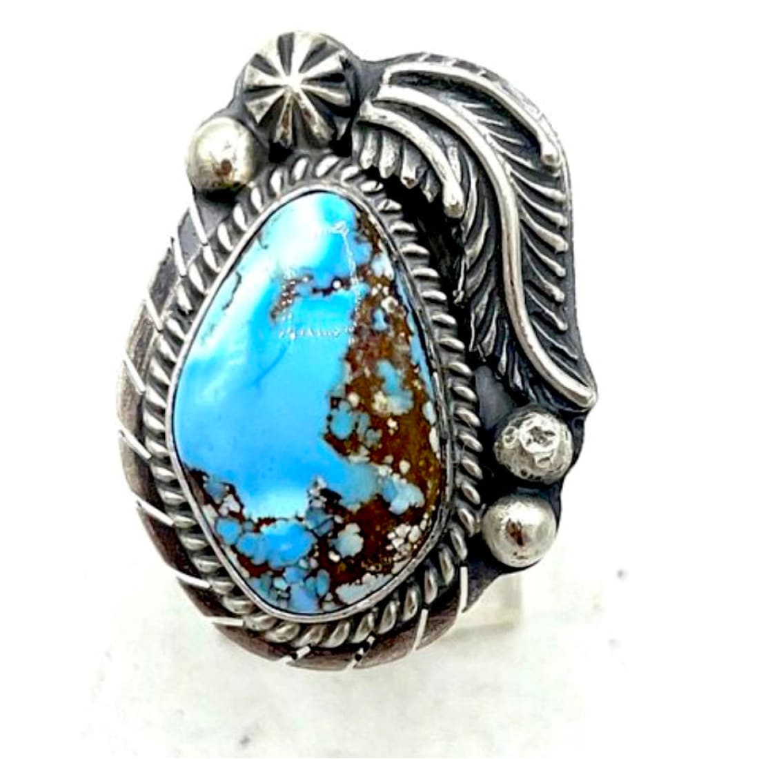 Navajo Golden Hills turquoise ring on a silver setting with intricate designs and a striking blue turquoise stone.