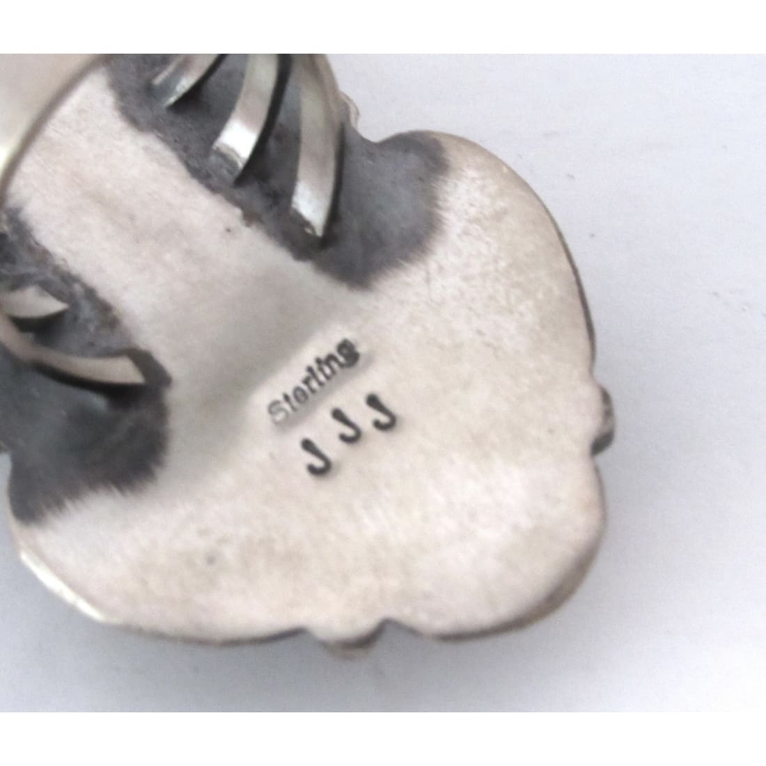 Close-up of Navajo red spiny oyster ring stamped sterling and JJJ maker's mark on silver
