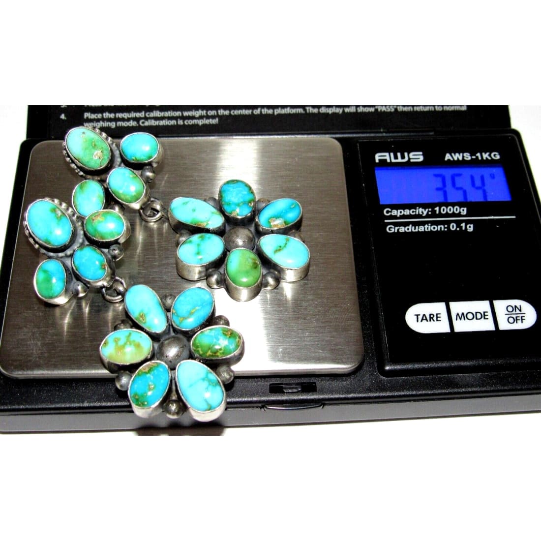 Sonoran gold turquoise dangle earrings with multiple turquoise stones displayed on a digital scale